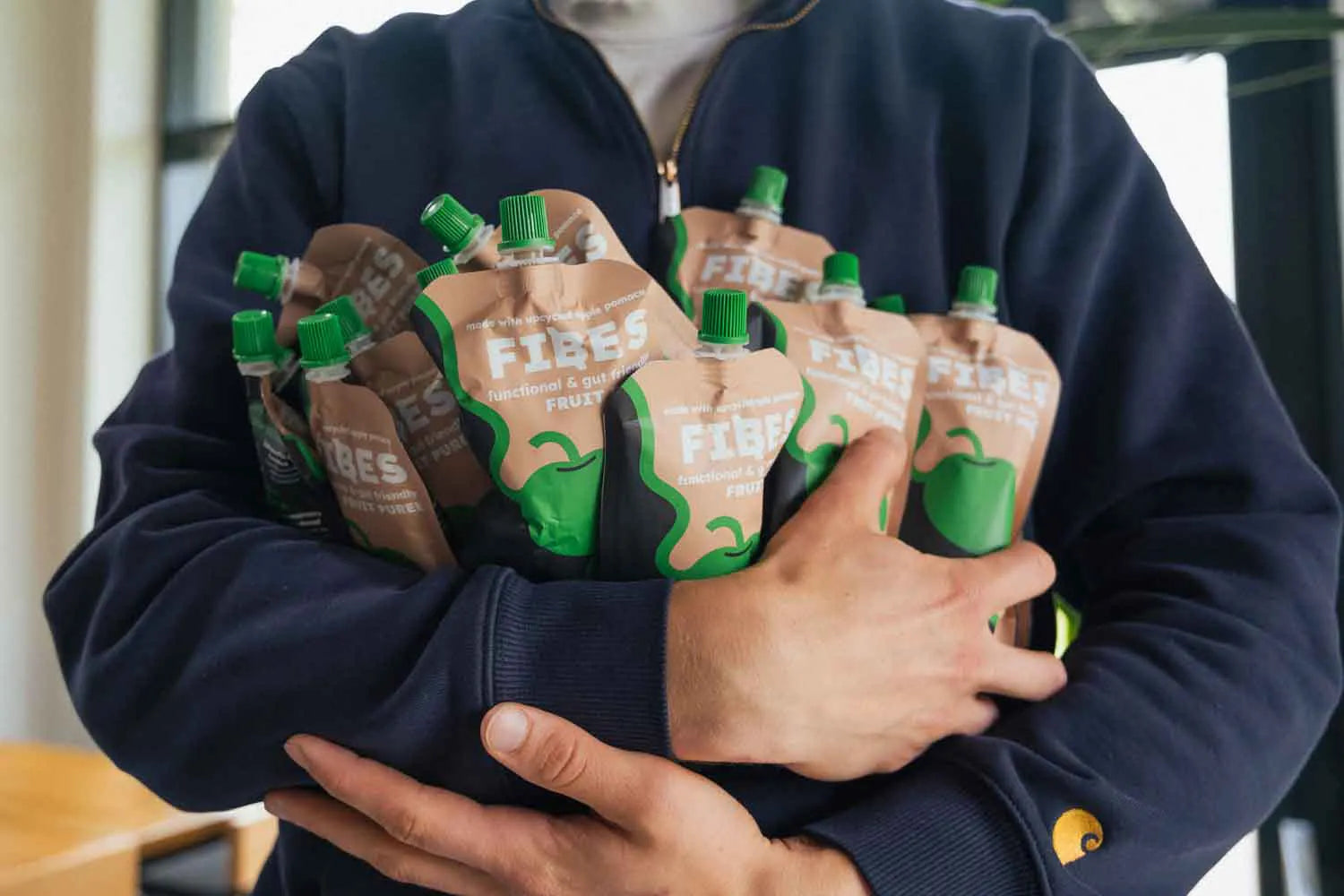 Person holding multiple pouches of Fibes in a casual setting
